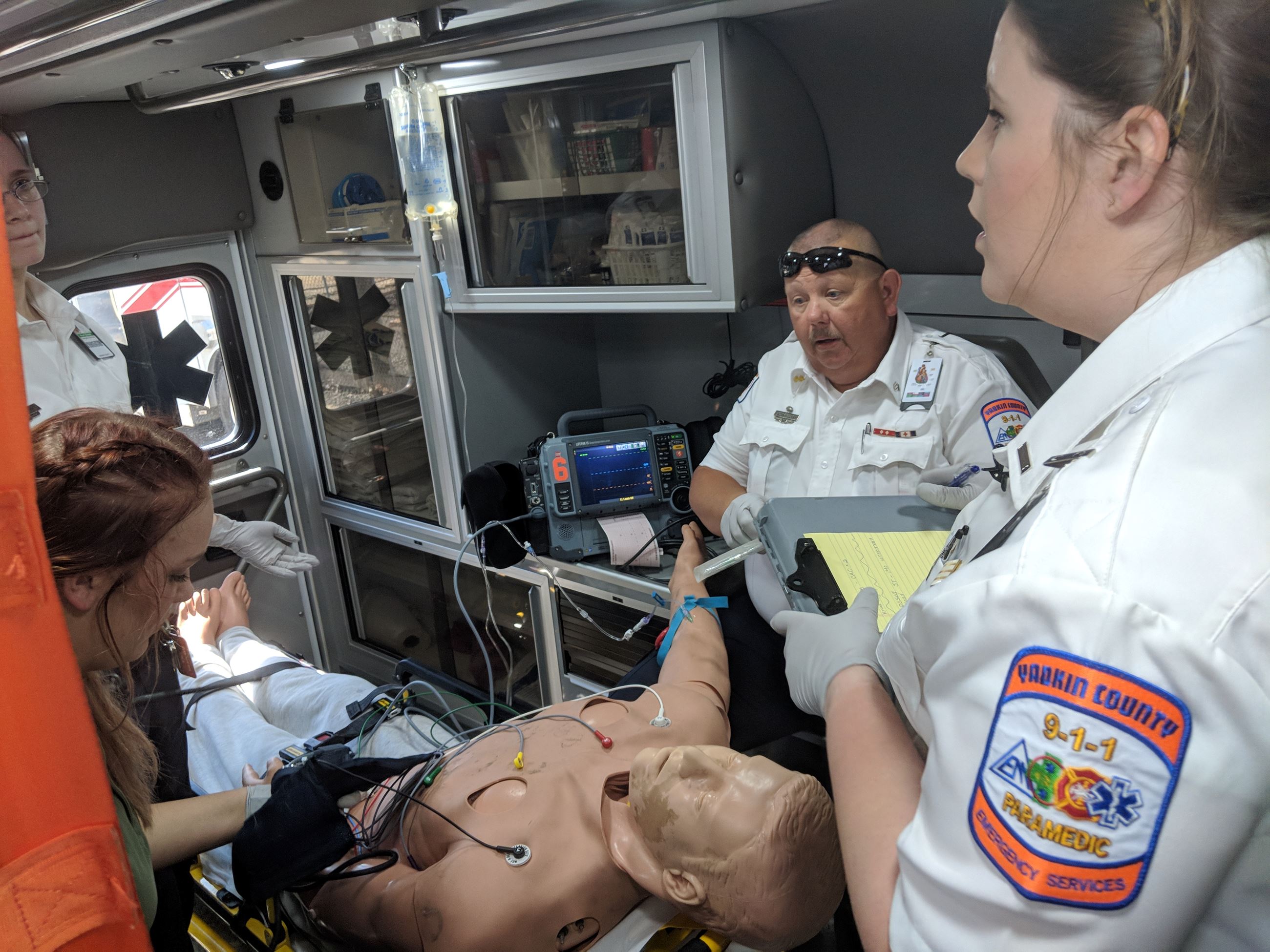 EMS employees conducting training in the back of an ambulance. 